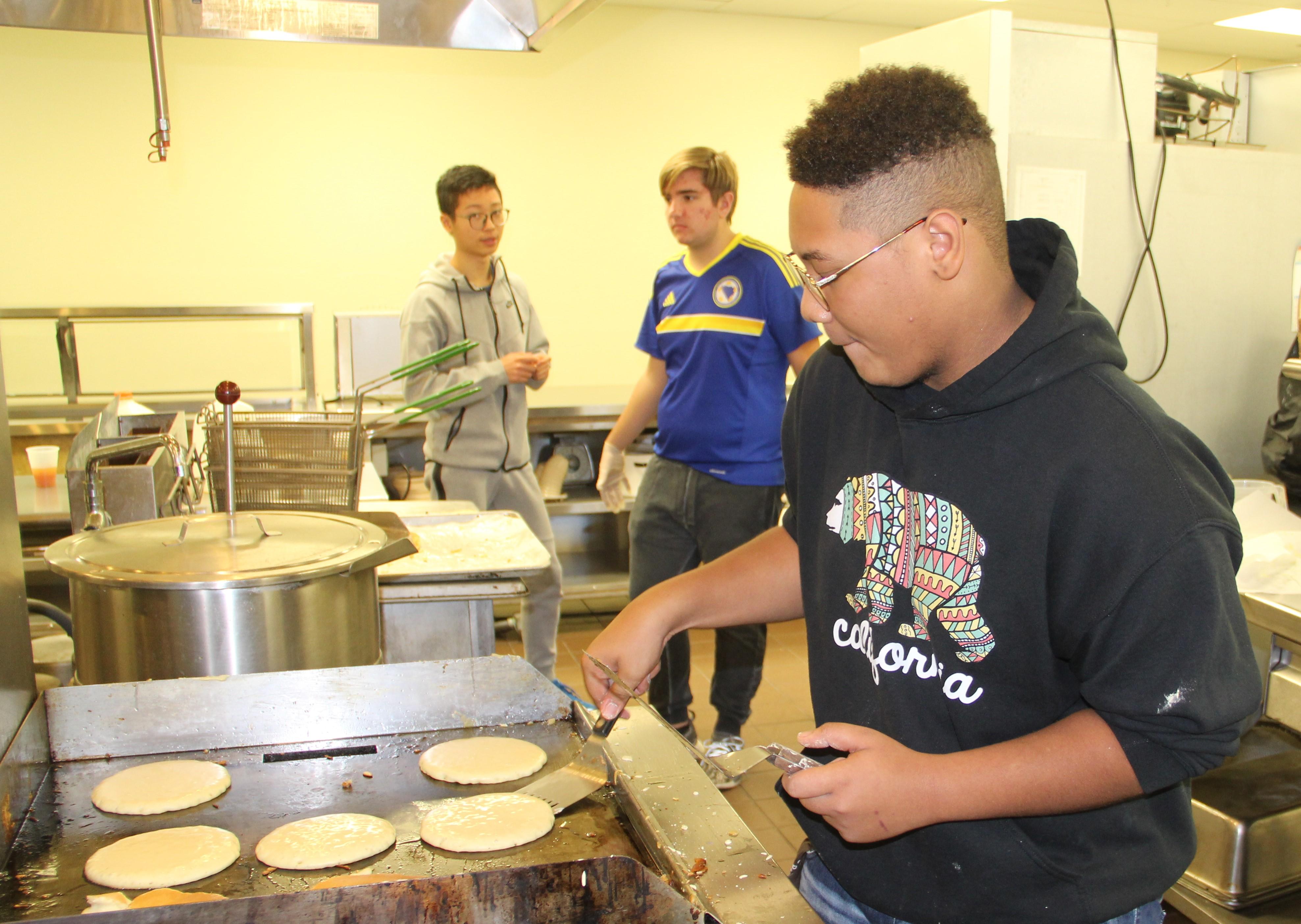 Upper School student preparing pancakes